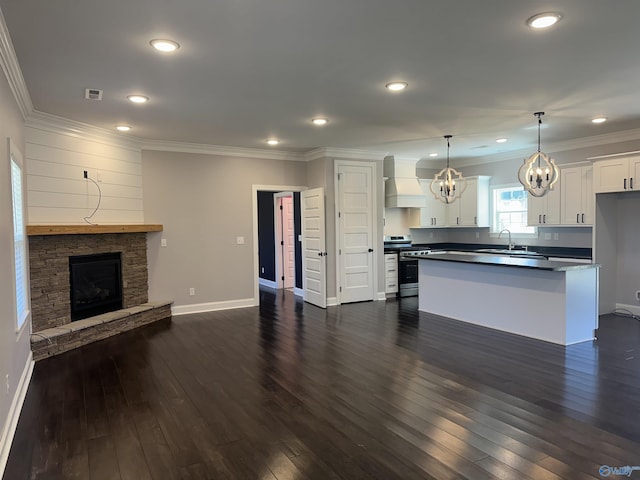 kitchen featuring visible vents, stainless steel range with gas cooktop, custom range hood, open floor plan, and a notable chandelier