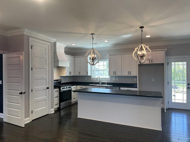 kitchen with a sink, premium range hood, stainless steel gas range oven, dark countertops, and an inviting chandelier