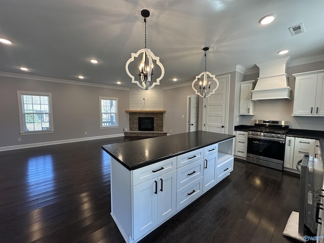 kitchen with custom range hood, an inviting chandelier, gas stove, dark countertops, and visible vents