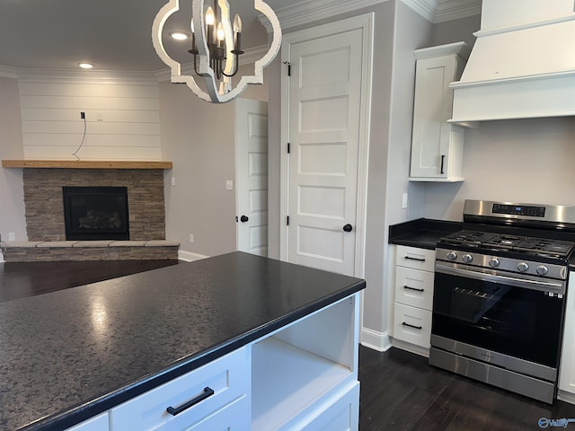 kitchen featuring white cabinets, custom exhaust hood, stainless steel range with gas stovetop, dark countertops, and a notable chandelier