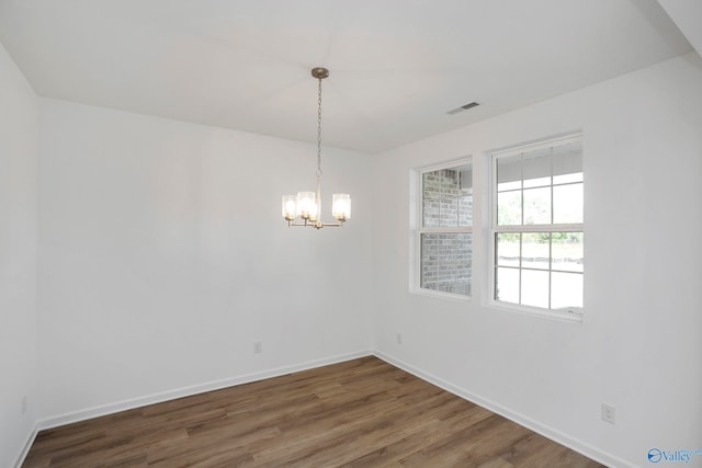 unfurnished room featuring dark wood-type flooring and a notable chandelier