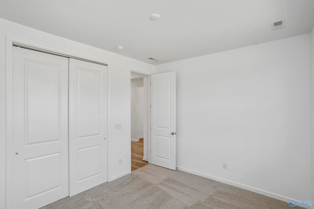 unfurnished bedroom with light colored carpet and a closet