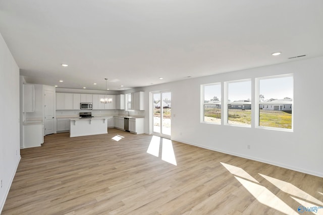 unfurnished living room featuring a chandelier and light hardwood / wood-style floors