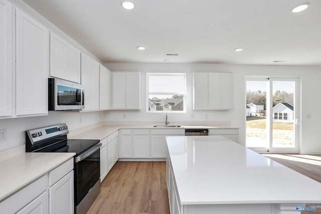 kitchen featuring white cabinetry, sink, a center island, stainless steel appliances, and light hardwood / wood-style flooring