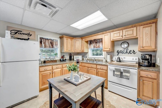 kitchen with light brown cabinetry, sink, white appliances, and a drop ceiling