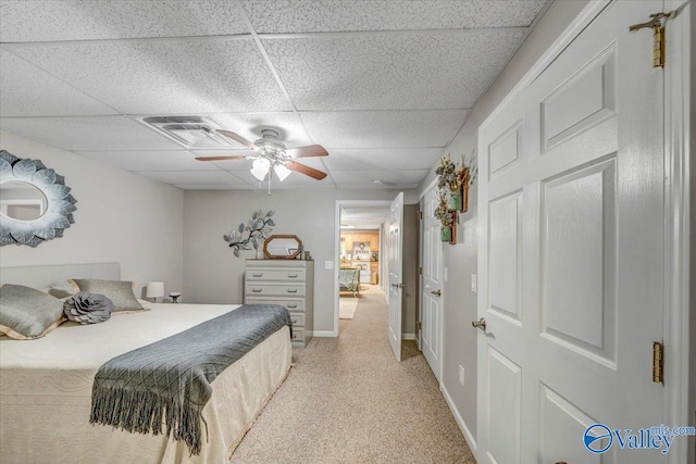 carpeted bedroom featuring ceiling fan and a drop ceiling