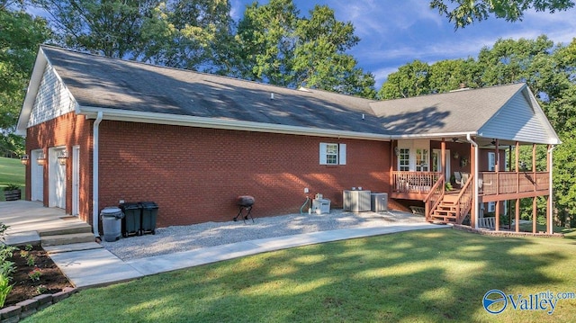 back of property featuring cooling unit, a garage, and a lawn