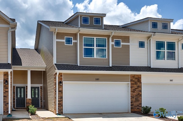 view of front of house with a garage, stone siding, concrete driveway, and roof with shingles