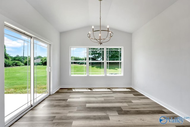 unfurnished dining area featuring vaulted ceiling, baseboards, wood finished floors, and an inviting chandelier