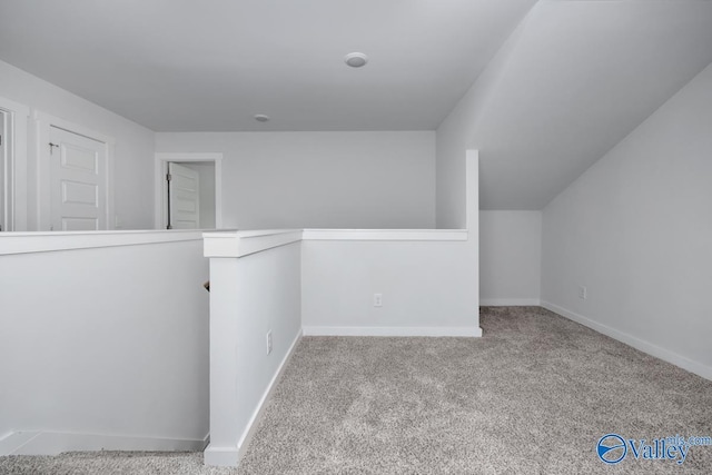 interior space featuring carpet, baseboards, and vaulted ceiling