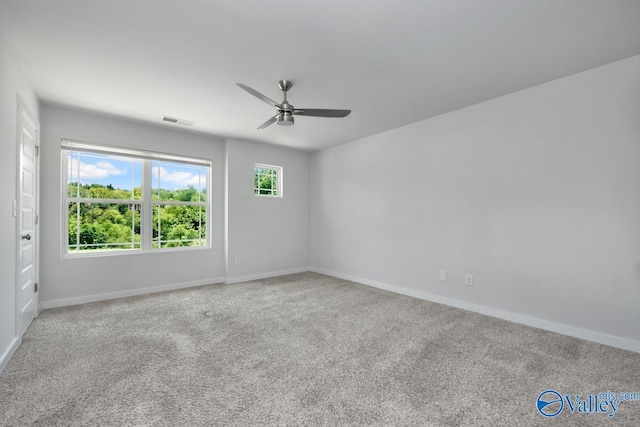 carpeted spare room with a ceiling fan, visible vents, and baseboards