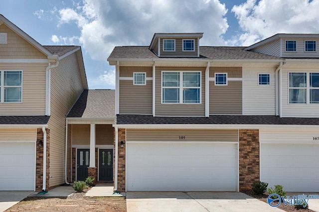 view of property with an attached garage, stone siding, concrete driveway, and roof with shingles