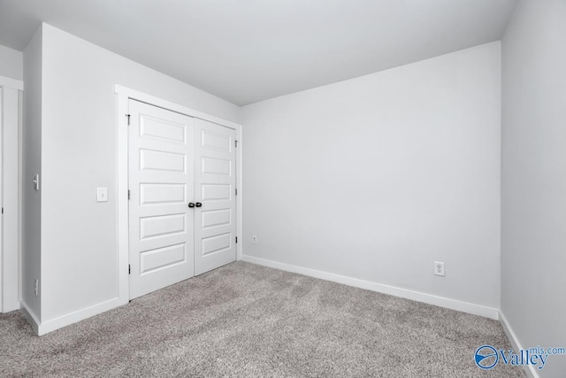 unfurnished bedroom with carpet floors, a closet, and baseboards