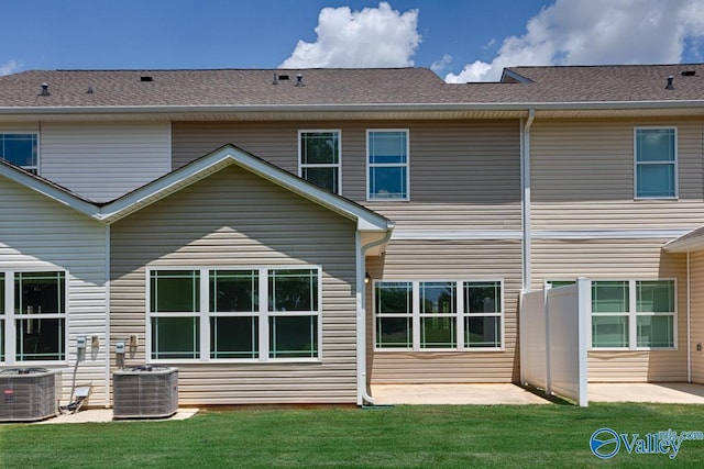 rear view of house with a patio area, a shingled roof, cooling unit, and a lawn