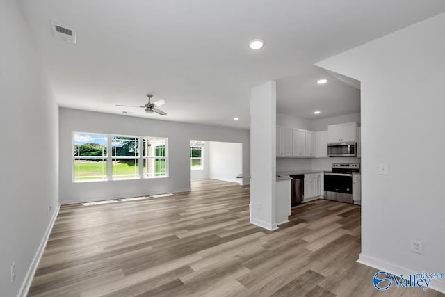 unfurnished living room with baseboards, light wood-type flooring, visible vents, and recessed lighting