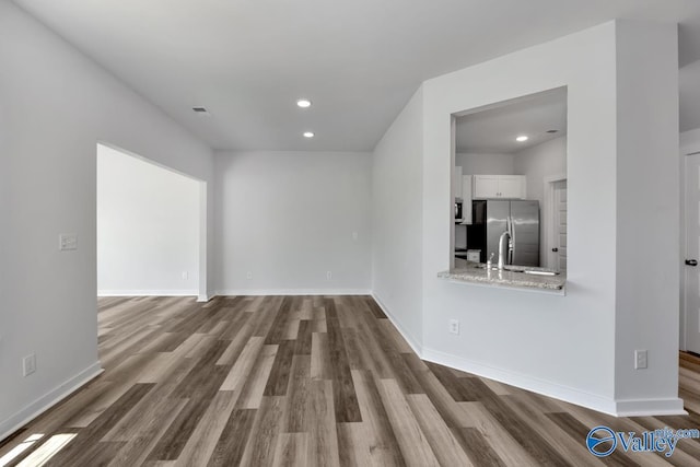 unfurnished living room featuring recessed lighting, a sink, baseboards, and wood finished floors