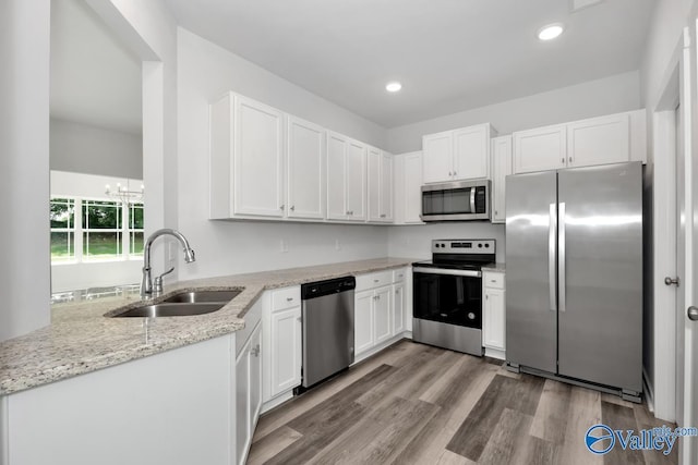 kitchen with stainless steel appliances, white cabinets, a sink, and wood finished floors