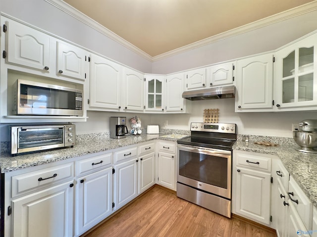 kitchen with appliances with stainless steel finishes, light wood-type flooring, white cabinetry, and ornamental molding