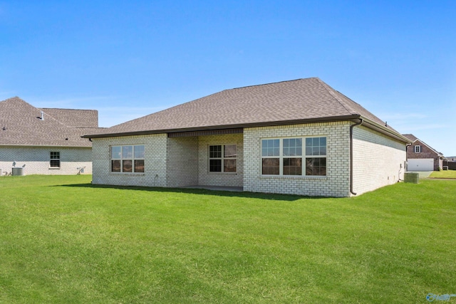 rear view of house with cooling unit, brick siding, a yard, and roof with shingles