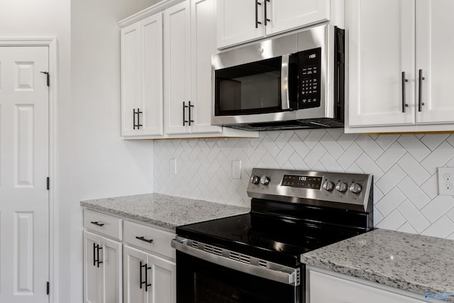 kitchen featuring light stone countertops, appliances with stainless steel finishes, white cabinets, and backsplash