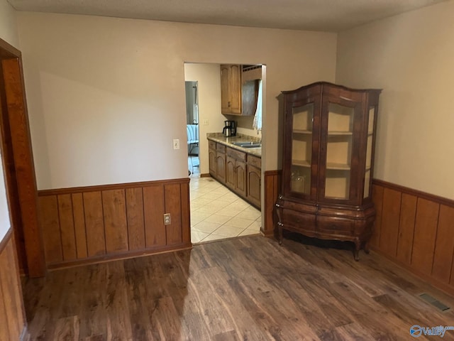 spare room featuring wainscoting, light wood-style floors, visible vents, and a sink