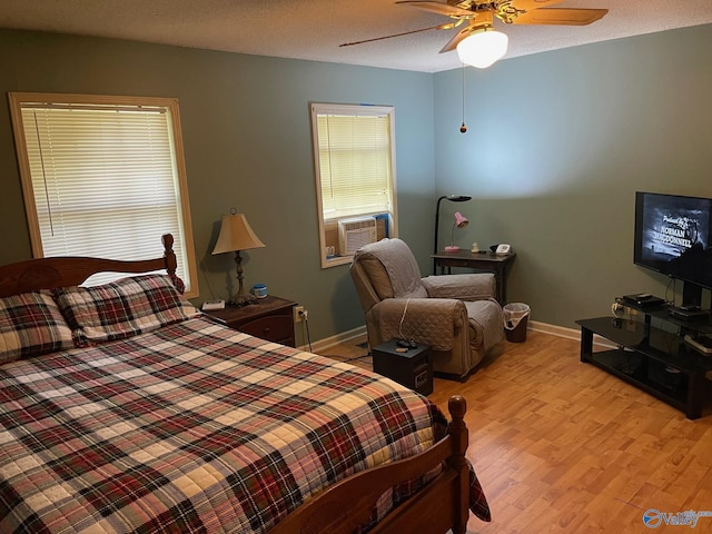 bedroom featuring ceiling fan, baseboards, cooling unit, and light wood finished floors
