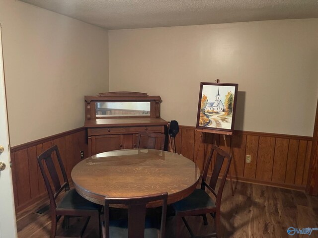 dining space featuring wooden walls, wood finished floors, and a wainscoted wall