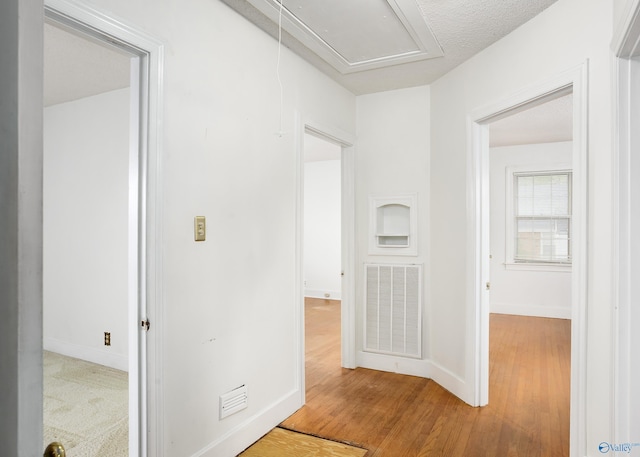 hall with wood finished floors, attic access, and baseboards