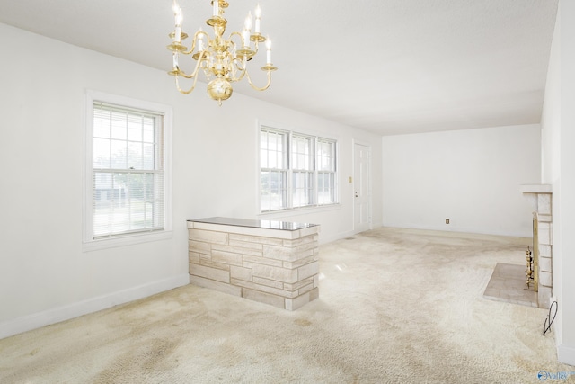 unfurnished living room featuring carpet, a chandelier, and baseboards