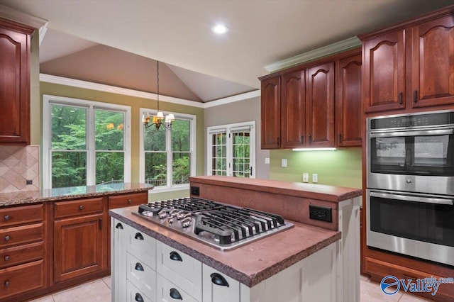 kitchen featuring tasteful backsplash, vaulted ceiling, appliances with stainless steel finishes, a notable chandelier, and white cabinets