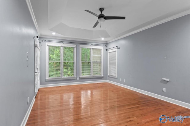 spare room featuring crown molding, ceiling fan, a tray ceiling, and light hardwood / wood-style floors