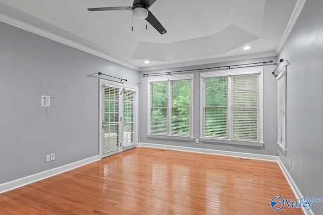 empty room featuring hardwood / wood-style floors, ornamental molding, a raised ceiling, and ceiling fan