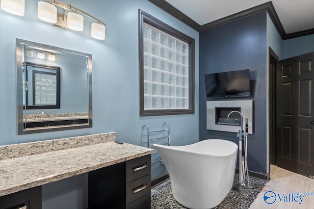 bathroom with vanity, crown molding, and a tub