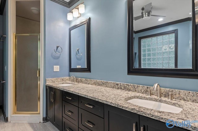 bathroom featuring vanity, a shower with door, and ornamental molding