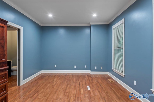 spare room featuring hardwood / wood-style flooring and ornamental molding