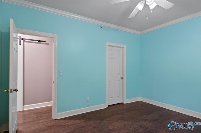 unfurnished bedroom featuring dark hardwood / wood-style flooring, crown molding, a barn door, and ceiling fan