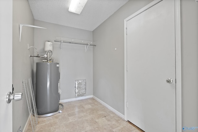 laundry area with water heater and a textured ceiling