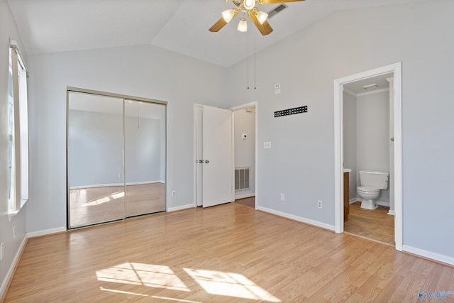 unfurnished bedroom with vaulted ceiling, connected bathroom, ceiling fan, light wood-type flooring, and a closet