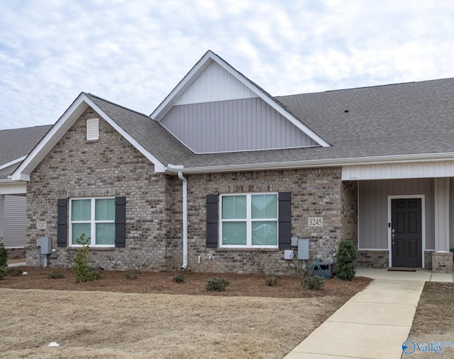 view of front of property featuring brick siding and roof with shingles