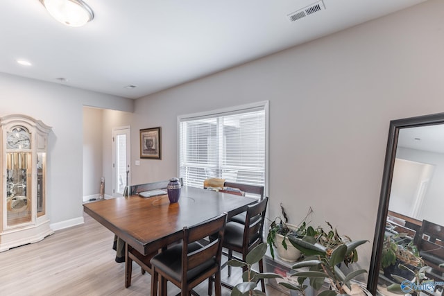 dining room featuring light wood-type flooring, visible vents, and baseboards