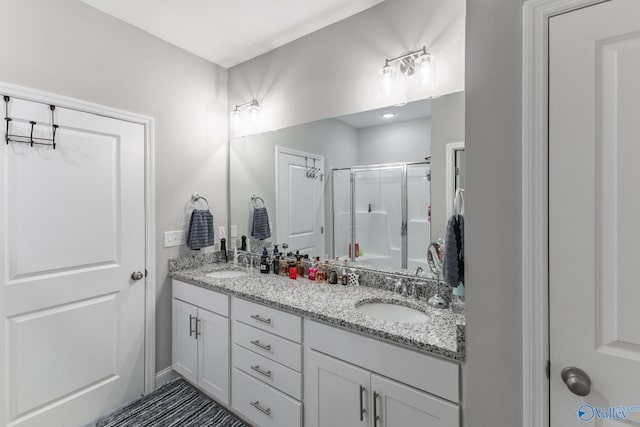 full bath with a stall shower, a sink, and double vanity