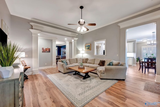 living room featuring ceiling fan, baseboards, ornamental molding, light wood finished floors, and ornate columns