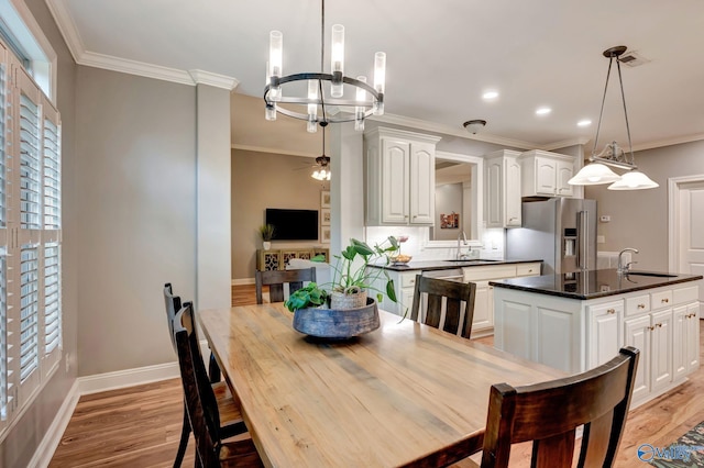 dining area with ornamental molding, an inviting chandelier, baseboards, and light wood-type flooring