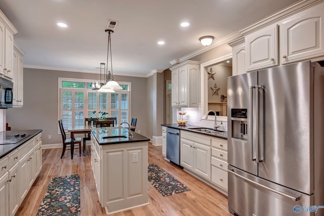 kitchen featuring appliances with stainless steel finishes, light wood-type flooring, baseboards, and a sink