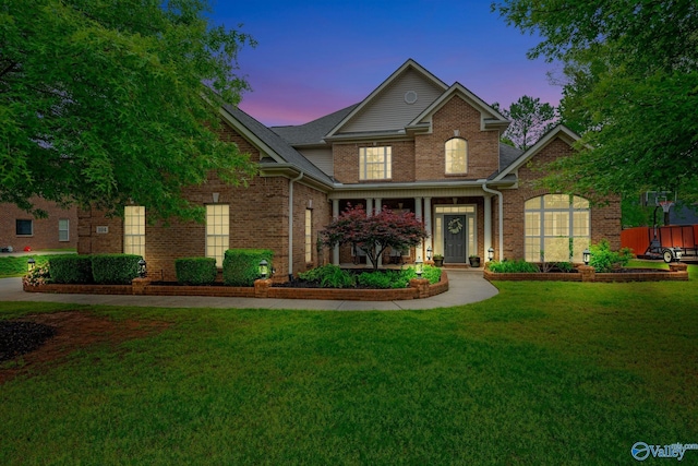 traditional home featuring brick siding and a yard