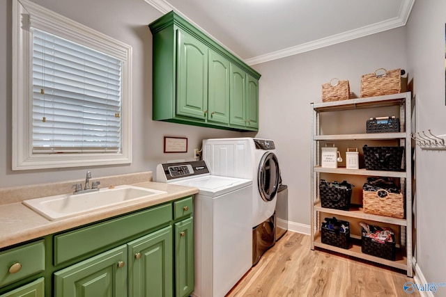 laundry area featuring a sink, cabinet space, light wood-style flooring, ornamental molding, and washer and dryer