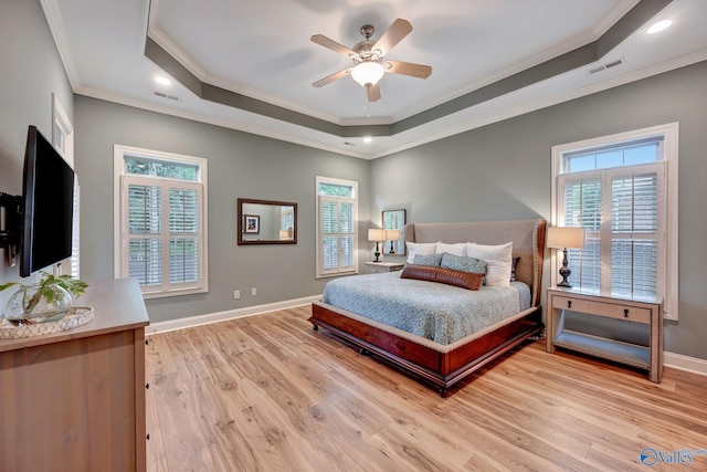bedroom with a raised ceiling, crown molding, visible vents, baseboards, and multiple windows