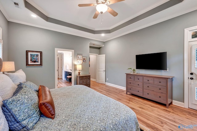 bedroom with ornamental molding, visible vents, light wood-style flooring, and a tray ceiling