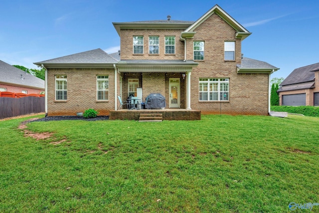 back of property with a lawn, brick siding, and fence