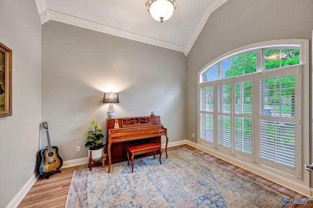 living area with crown molding, wood finished floors, lofted ceiling, and baseboards